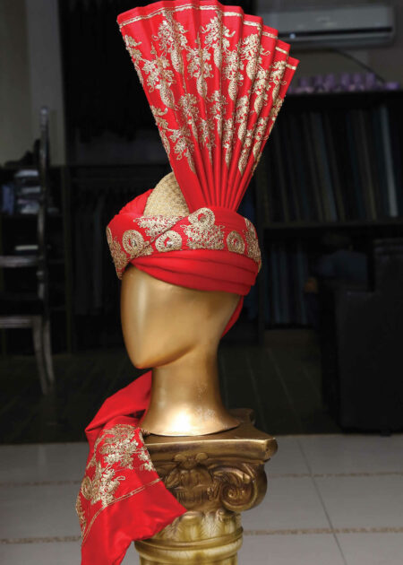 A close-up of a red embroidered turban with intricate patterns